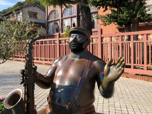 マスクをしたサックスを吹いている半裸の銅像